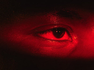 Close-up of a person's eyes lit in deep red light, illustrating chronic inflammation and healthspan