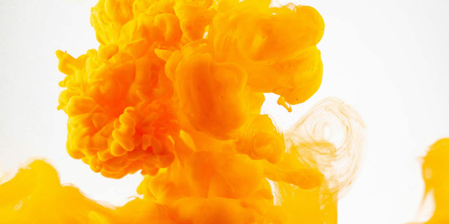 Yellow ink spreading evenly through clear water, illustrating curcumin dispersing in the gut