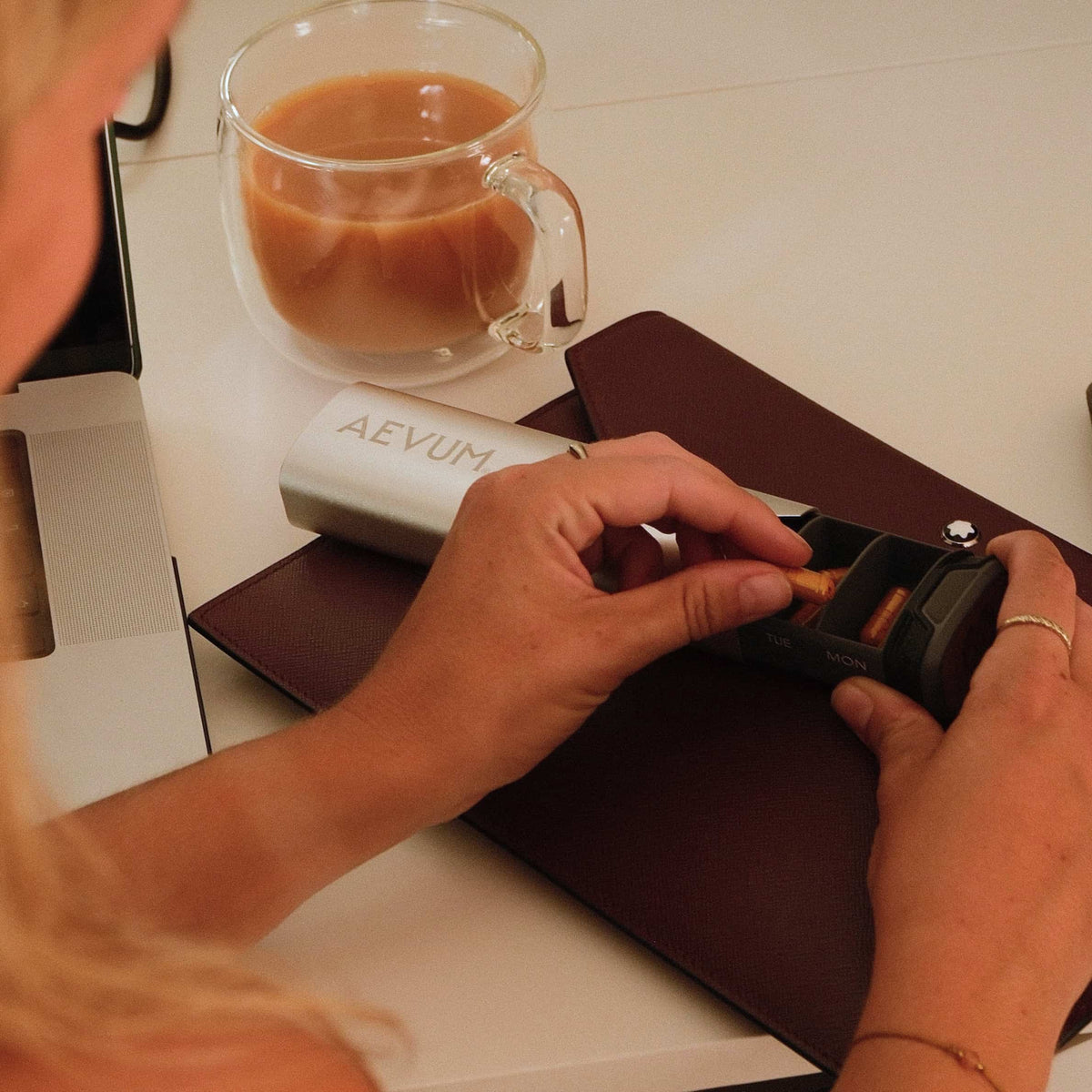 AEVUM travel pill case on desk with coffee, morning routine